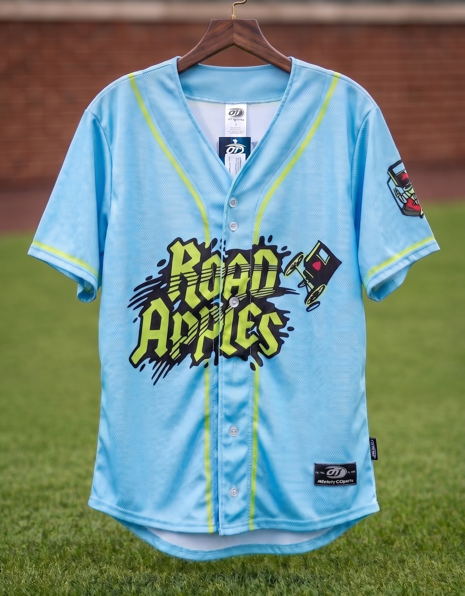 Light blue baseball jersey with 'Road Apples' text on a grass field background